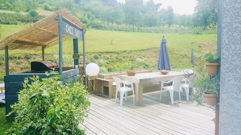Terrasse avec table en bois et abris à barbecue